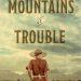 Cover art for Mountains of Trouble. Woman in red dress looking toward mountains.