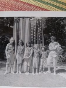 Six little girls and their mother in front of a flag